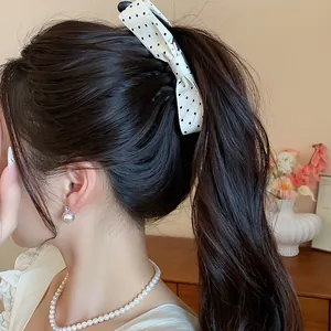 Detailed view of sweet white polka dot bow banana hair clip worn on a ponytail accessory.