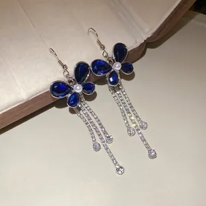Close-up of elegant blue teardrop crystal floral earrings with long diamond tassel detail.
