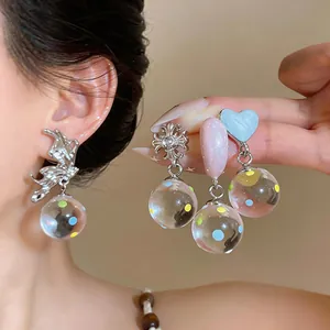 Detailed shot of silver heart, butterfly and gothic cross earrings with glass ball charms