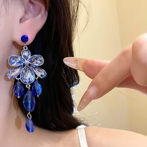 Detailed view of elegant blue crystal floral teardrop dangle earrings on model's ear