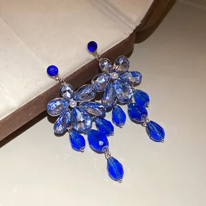 Close-up of elegant blue crystal floral drop earrings resting on a jewelry box