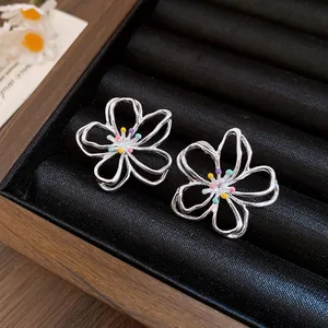 Nahaufnahme von eleganten silbernen hohlblumen-ohrringen mit bunten staubbeuteln