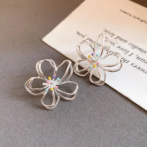 Detailaufnahme von silbernen hohlen Blumenohrsteckern mit farbenfrohen Akzenten in der Mitte