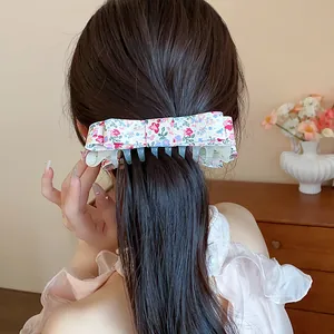 Close-up view of a sweet floral fabric bow hair claw clip being worn in a stylish semi-updo