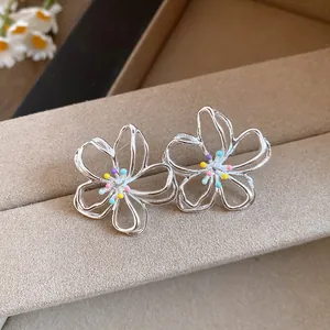 Detailaufnahme der silbernen hohlen Blumenohrstecker mit bunten Perlen in der Mitte