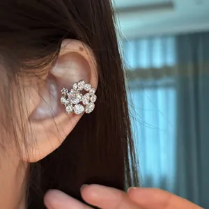 Detailed view of elegant silver flower earring set with sparkling zircon stones on model's ear