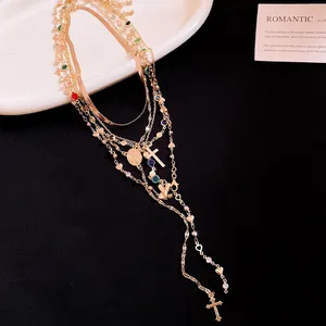 Primo piano di una collana dorata a più strati con cristalli colorati e ciondoli a croce