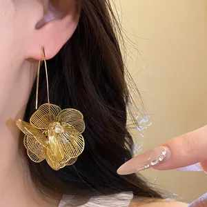 Detaillierte Ansicht eleganter goldener hohler Metallblumen-Ohrhänger am Ohr eines Modells