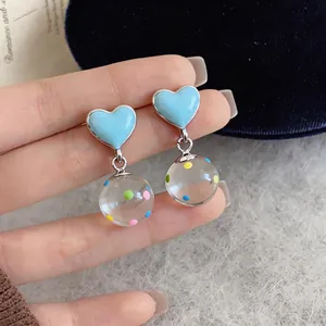 Detailed close-up of blue heart stud earrings featuring colorful polka dot glass ball drops