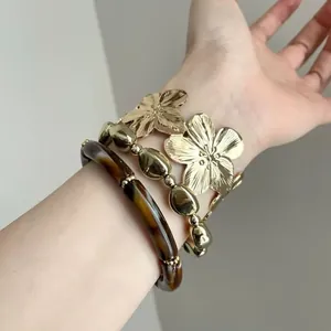Close-up detail of vintage gold flower bangles and tortoiseshell bracelet set for women
