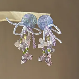 Gros plan sur des boucles d'oreilles en perles lilas avec des cristaux féeriques