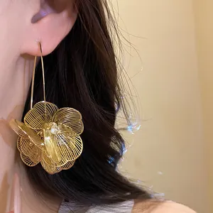 Detailansicht goldener hohler Blumenohrring am Ohrmodell für einen eleganten Look.
