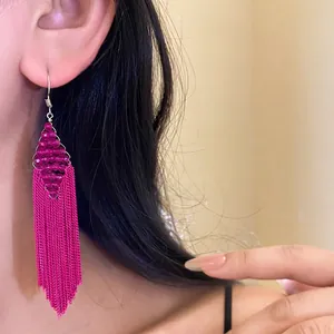 Boucles d'oreilles à pompons fuchsia bohèmes avec perles en acrylique sur un modèle