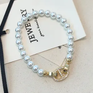Nahaufnahme eines eleganten Perlenarmbands mit einem goldfarbenen, zirkoniabesetzten Verschluss.