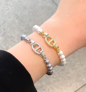 Detailansicht von eleganten Perlenarmbändern mit Zirkon-Schweinennasenverschluss am Handgelenk.