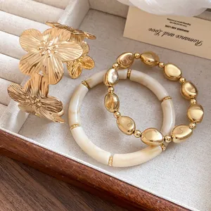 Vintage gold floral cuff bracelet paired with cream and gold beaded bangles for women