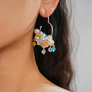 Detailed close-up view of colorful dopamine style flower and pearl beaded hoop earrings on ear