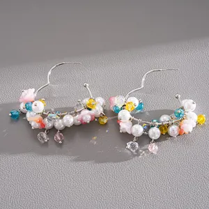 Detailed view of colorful glass beads and faux pearls on silver-tone heart hoop earrings.