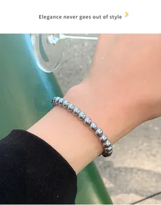 Detailansicht eines eleganten grauen Perlenarmbands an einem weiblichen Handgelenk