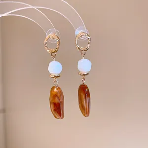 Detailed view of Maillard style amber resin drop earrings featuring white faceted beads
