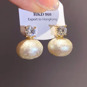 Detail of vintage earrings with sparkling zircon and large textured cotton pearls