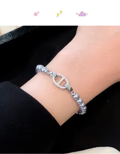 Nahaufnahme eines silbernen Perlenarmbands mit einem funkelnden, strassbesetzten Ankerverschluss.