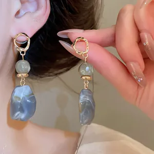 Detail showing irregular resin geometric earrings in Maillard style worn on ear