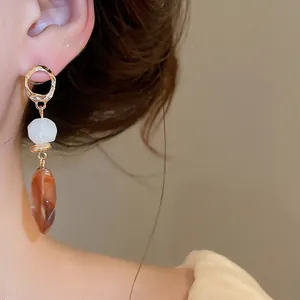 Close-up detail of Maillard style resin geometric drop earrings worn on an ear