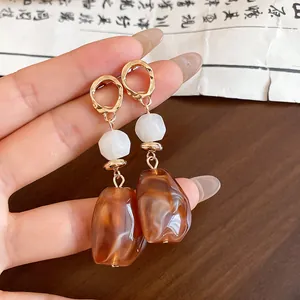 Macro view of Maillard style resin earrings with irregular geometric amber drops