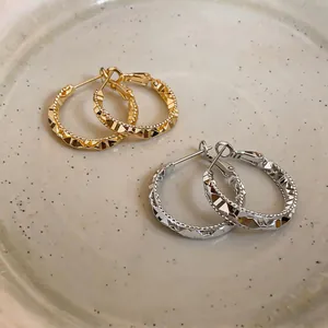 Detailed macro shot of French vintage gold and silver hoop earrings with faceted texture
