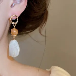 Detail of Maillard resin earrings with irregular geometric white marble drop
