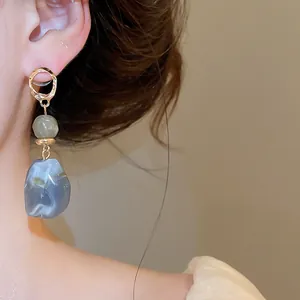 Detailed view of women's irregular blue-grey marble resin geometric drop earrings