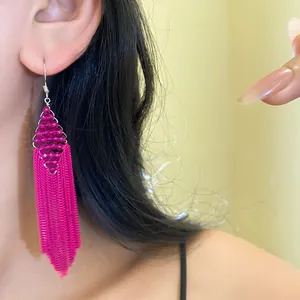Gros plan d'une boucle d'oreille bohème vibrante à pompons en perles acryliques magenta