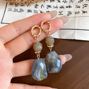 Detailed shot of irregular marbled resin geometric drop earrings in gold setting