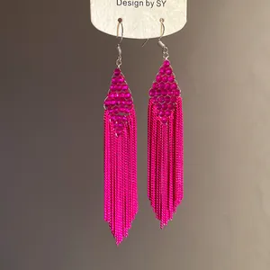Gros plan de boucles d'oreilles à pompons rose fuchsia avec chaînes en métal