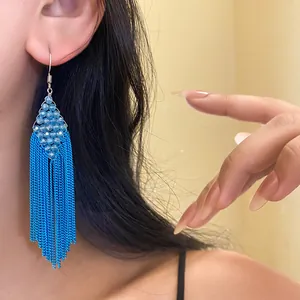 Détail d'une boucle d'oreille bohème bleue avec perles acryliques et franges.