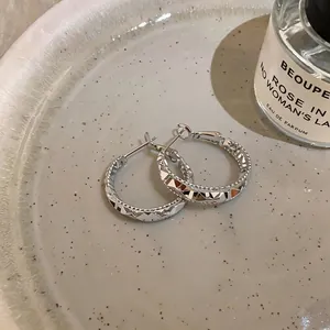 Detailed view of silver hoop earrings with faceted geometric texture in vintage style