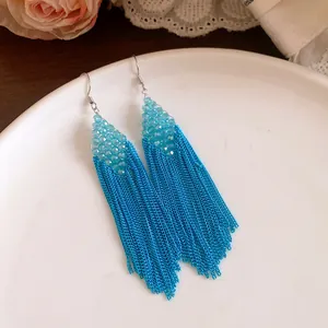 Gros plan sur des boucles d'oreilles bohèmes à perles bleues et longues franges.