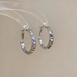 Close-up detail of French retro style geometric faceted silver hoop earrings with latch-back
