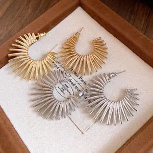 Detailed view of elegant gold and silver sunburst C-shaped earrings in a box.