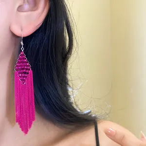 Gros plan de boucles d'oreilles élégantes à pampilles fuchsia portées par un mannequin.