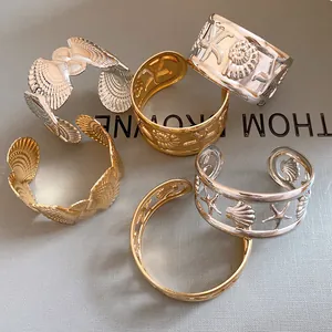 Detailed view of the gold and silver sea star and shell hollow open cuff bangles.