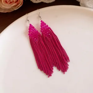 Vue détaillée des boucles d'oreilles à pompons en perles acryliques magenta bohème.