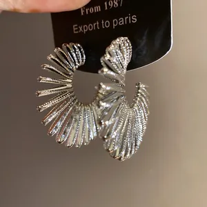 Close-up of silver-toned C-shaped hoop earrings with spiral pleated texture on card