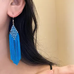 Gros plan détaillé de boucles d'oreilles bohèmes à pampilles en perles acryliques bleues
