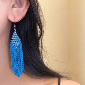 Détail de boucle d'oreille bohème à franges de perles bleu vif porté par un mannequin