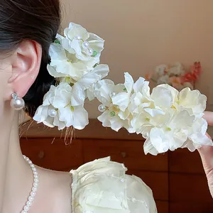 Close-up of elegant white fabric flower hair clip featuring delicate pearl accents