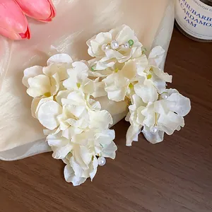 Detailed view of ethereal cream fabric flower hair clips with elegant pearl accents