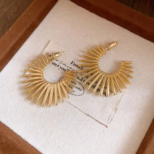 Detailed view of gold sunburst C-shaped hoop earrings with radial metal beams
