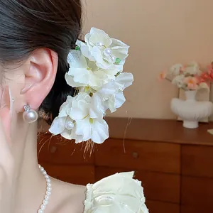 Detailed side view of an elegant fabric flower hair clip with pearl accents in hair